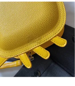 Detail of bright yellow crossbody bag showing lychee pattern leather and neat stitching