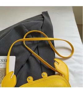 Detail of creative yellow crab-shaped crossbody bag with lychee texture and rivet eyes