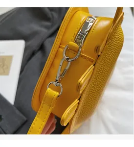 Detail of silver zipper and D-ring on yellow lychee texture leather crossbody bag
