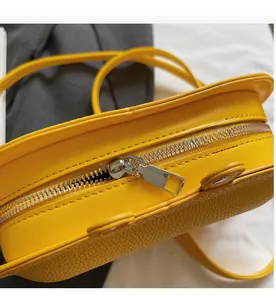Close-up of smooth metal zipper and lychee pattern faux leather on bright yellow bag