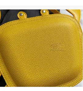 Close-up of yellow lychee pattern leather and crab bag detail on denim background