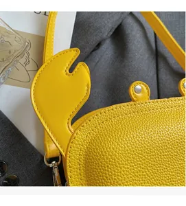 Detail of yellow crab-shaped crossbody bag featuring lychee texture and metallic rivets
