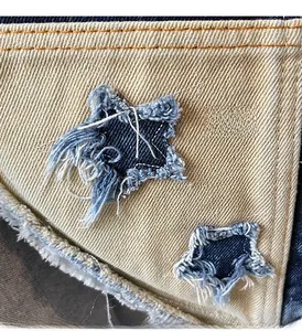 Detail of denim star patches with frayed edges and vintage stitching on canvas bag