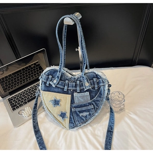Detailed close-up of heart-shaped denim bag with fringed edges and star patchwork design