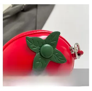 Gros plan sur le mini sac pomme rouge avec détail de feuille verte et zip argent