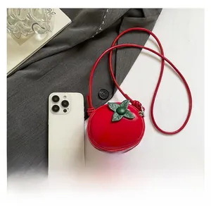 Détail du mini sac bandoulière rouge en forme de tomate avec feuille et téléphone