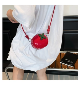 Détail du mini sac bandoulière rouge en forme de tomate avec décor de feuilles vertes