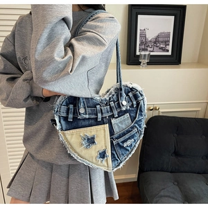 Detail of heart-shaped denim shoulder bag with frayed edges and star patchwork