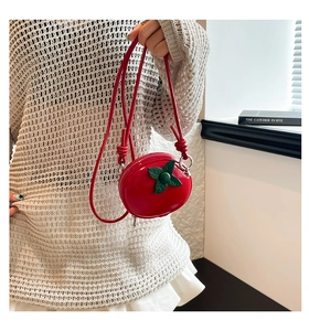 Détail du mini sac bandoulière en forme de fruit rouge avec accents de feuilles