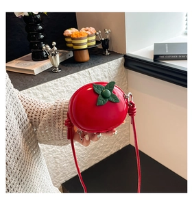 Détail du mini sac bandoulière rouge en forme de pomme avec décor de feuilles et zip