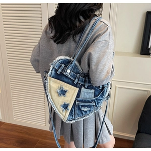 Detail of heart-shaped denim handbag with frayed edges and star embroidery design