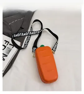 Close-up of bright orange carrot-shaped crossbody bag with ribbed texture and LOVE strap