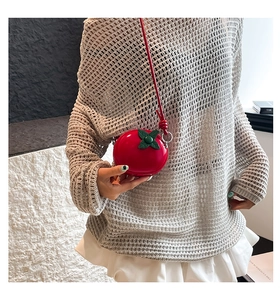 Détail du mini sac bandoulière rouge en forme de tomate porté avec une fine lanière