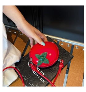 Vue détaillée du mini sac tomate rouge avec détail de feuille verte et fine bandoulière