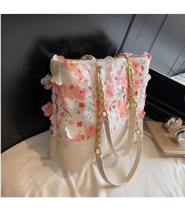 Détail d'un sac cabas floral avec chaîne dorée et décoration de fleur en tissu 3D