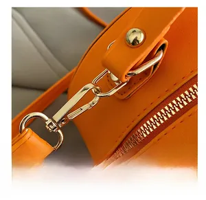 Détail du crochet en métal doré et du cuir orange texturé sur un sac à bandoulière rond