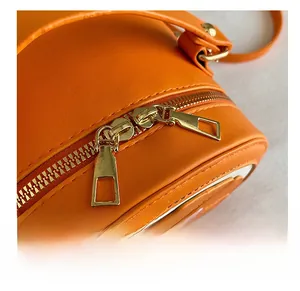 Détail des doubles fermetures éclair dorées et coutures du sac à bandoulière orange