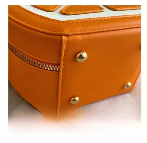 Gros plan du sac en cuir orange avec des clous en métal doré et des coutures précises