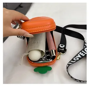 Internal storage detail of carrot-shaped crossbody bag with phone and lipstick items