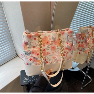 Détail du sac seau en cuir blanc avec appliques florales 3D et bandoulière en chaîne