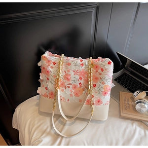 Détail du sac cabas en tissu blanc avec fleurs 3D roses et oranges et chaîne dorée