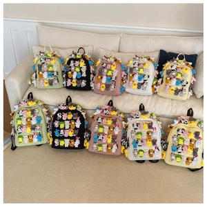 Close-up of cute canvas backpacks with various small plush animal dolls and multiple colors