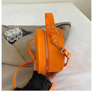 Vue détaillée du sac rond citron orange avec fermetures dorées et texture en cuir synthétique