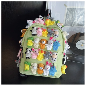 Detail of light green canvas backpack decorated with colorful plush animal finger puppets