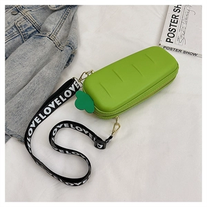 Detail of green rectangular box bag with leaf charm and wide LOVE letter strap