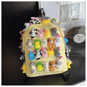 Detail of yellow nylon backpack featuring various cute plush animal finger puppets