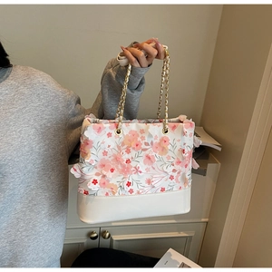 Détail d'un sac cabas floral avec fleurs 3D et bandoulière en chaîne dorée brillante