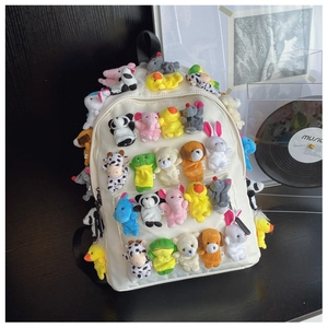 Close-up of white canvas backpack featuring colorful plush mini animal dolls detail
