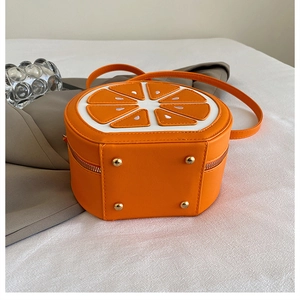 Détail du sac bandoulière orange avec fermeture éclair et picots de protection dorés