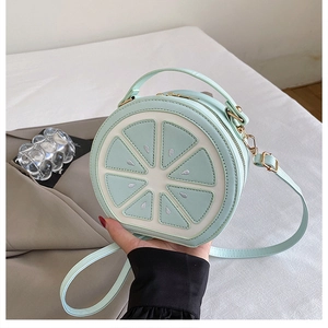 Vue détaillée du sac citron rond avec surpiqûres vert menthe et fermeture éclair dorée