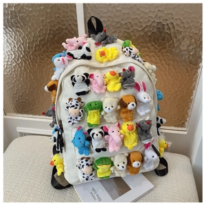 Close-up of white canvas backpack decorated with multiple cute plush animal dolls