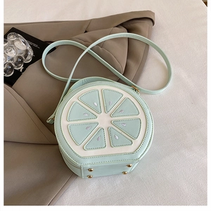 Détail du sac rond citron vert menthe avec texture de couture et pieds dorés