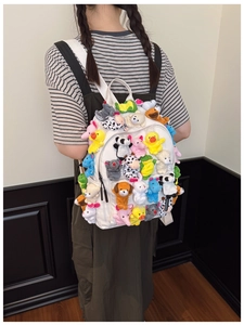 Close-up of white backpack decorated with colorful plush cartoon animal finger puppets
