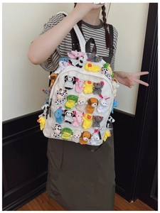 Detailed view of white canvas backpack decorated with colorful plush animal charms on a model