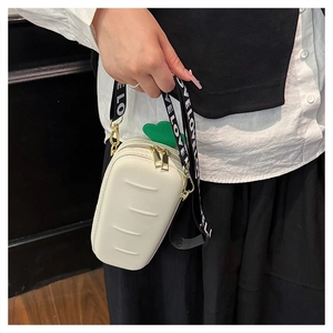 Detail view of cream white carrot-shaped crossbody bag with green leaf top and wide strap