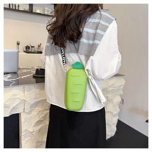 Macro view of green silicone carrot-shaped crossbody bag with lettered wide strap
