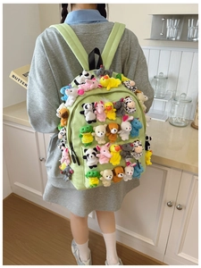 Close-up of a green backpack decorated with many small plush animal toys on the front