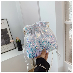 Detail of white sequin bucket bag featuring a drawstring closure and gold chain strap