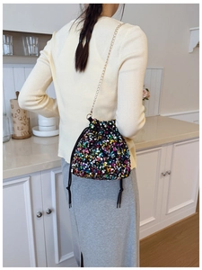 Detail of colorful sequin bucket bag featuring a gold chain strap and drawstring closure