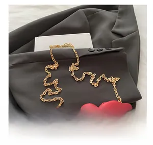 Macro shot of red floral evening bag featuring chunky gold metal chain strap detail