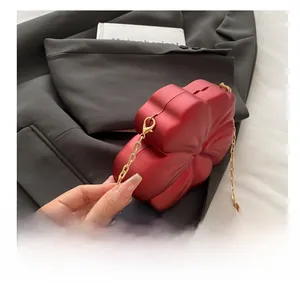 Macro detail of red floral evening clutch on a black blazer with golden chain strap