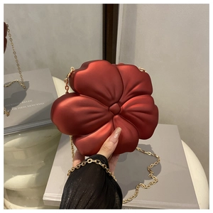 Detailed close-up of a red flower-shaped evening clutch bag with a delicate gold chain strap