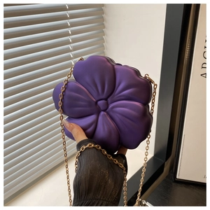 Detailed close-up of a purple acrylic flower clutch with matte texture and gold chain strap