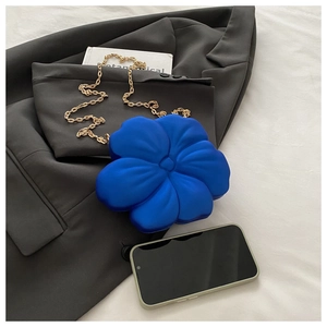 Detailed view of Klein blue flower acrylic evening bag with gold chain on dark grey suit