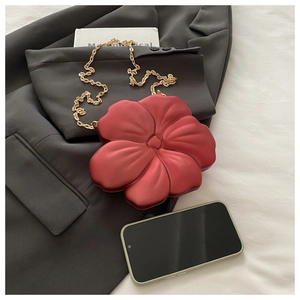 Macro shot of 3D red flower acrylic clutch bag featuring elegant gold metal chain