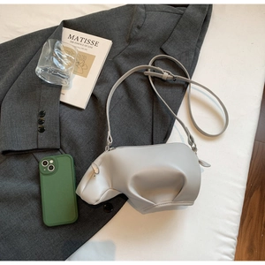 Vue à plat d'un sac à bandoulière hippopotame gris clair avec accessoires de style